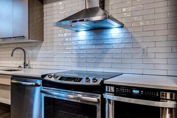 A modern kitchen with a stainless steel oven and a range hood above it.